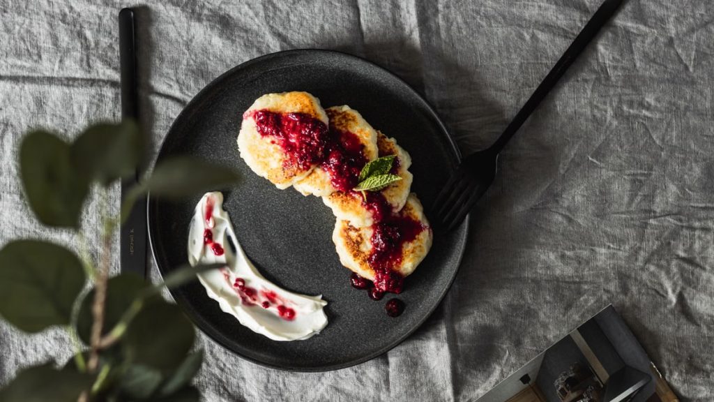 Tasty pancakes topped with fresh berry sauce on a ceramic plate, perfect for a gourmet breakfast.